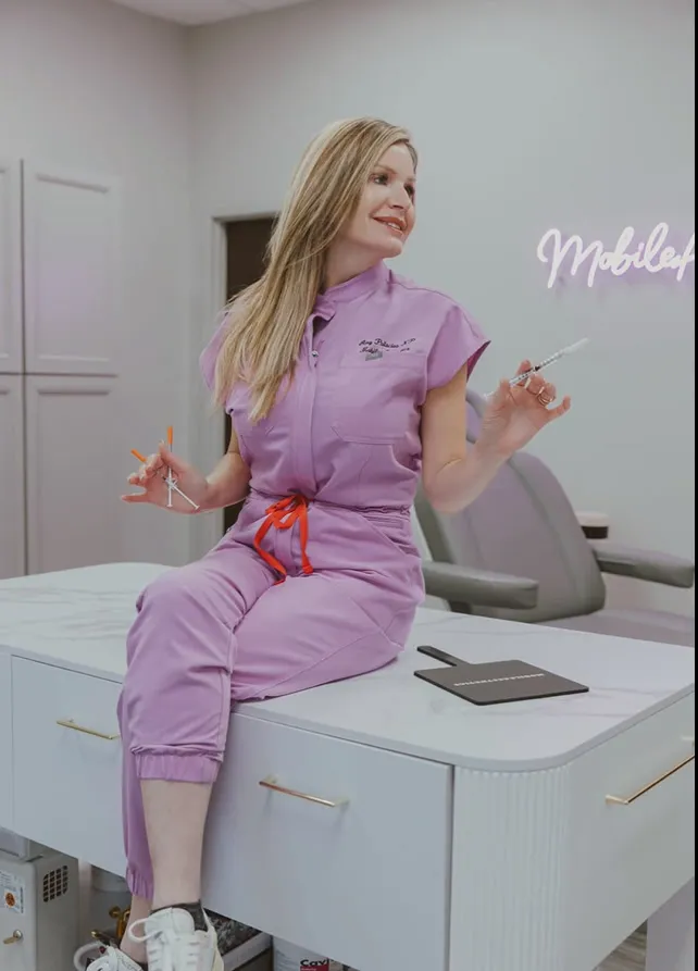 Amy Palacios, FNP, seated on the studio counter