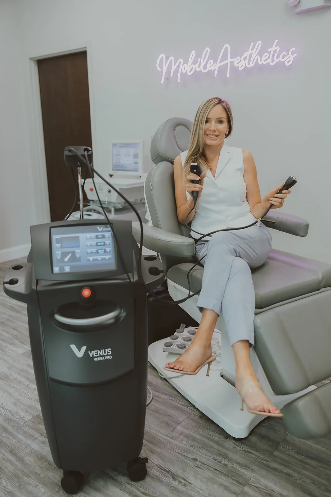 Amy Palacios, FNP, seated in the treatment chair holding two Venus Versa Pro applicators.